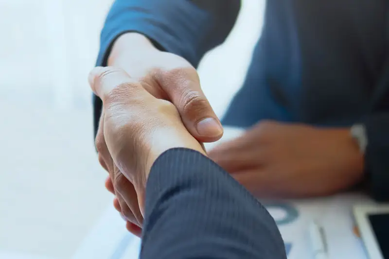 Two business people shaking hands over a table