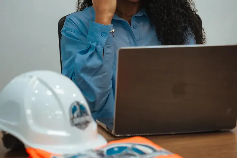 Labour Pro Group team member on the phone at a desk with laptop, hard hat and hi-vis vest