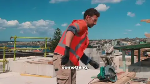 Ticketed worker in hi-vis and safety glasses checking a saw on a rooftop site — Safety Matter video
